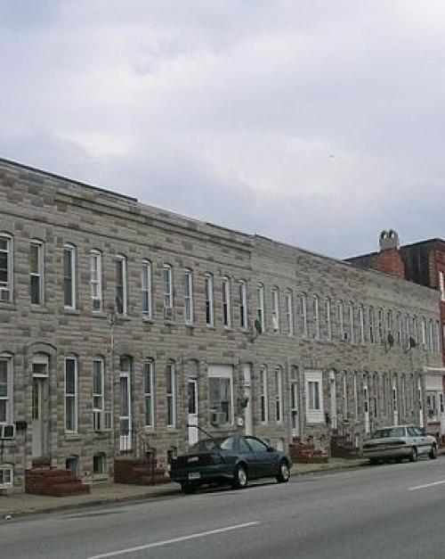 A long line of two-story rowhouses, all one color except for one red brick house.